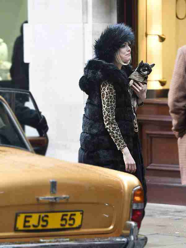Emma Stone wearing a black faux fur coat on the set of Cruella 2021